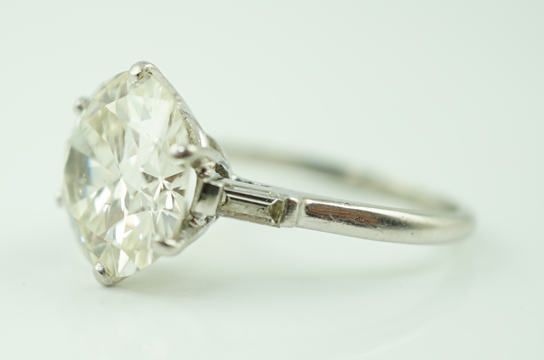 A platinum and single stone diamond set ring, with baguette cut diamond set shoulders